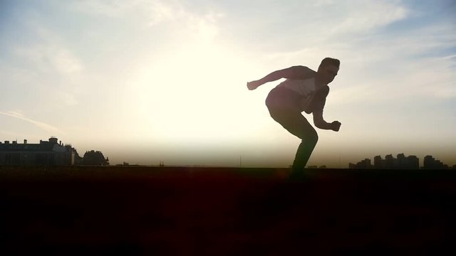 Slow-motion - young male Parkour tricker jumper performs amazing flips in front of the sun