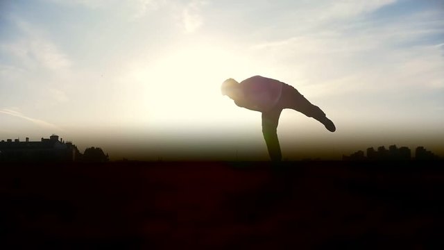 Slow-motion - young male Parkour tricker jumper performs amazing flips in front of the sun