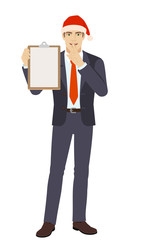 Businessman in Santa hat holding the clipboard and making hush sign