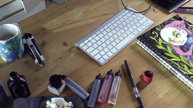 Close up shot of unrecognizable male illustrator finishing his artwork made in sketchbook when sitting at desk full of art supplies