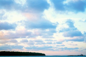 Obraz premium The vast blue sky and clouds sky over the sea. Blue sky and clouds for background, Sun rays bursting through the clouds, Cloud sun beam ray light warm orange color Dramatic background