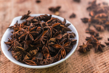 Close up of anise stars in bowl on wooden background