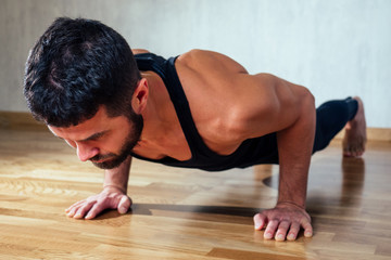 Fototapeta na wymiar A muscular man does exercises to strengthen the muscles of the hands on the floor. push-up from the floor. concept of health promotion and beautiful body