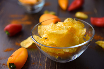 Potato chips with paprika on dark wooden background