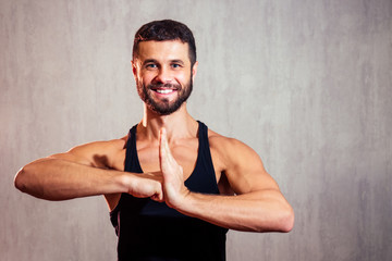 portrait of a handsome young man in a black T-shirt on a gray background. sports man smiling and...