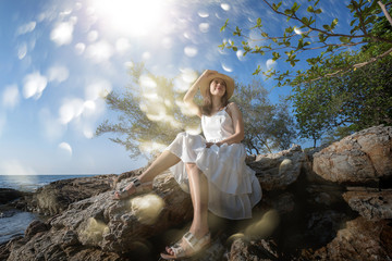 Portrait of Asian beautiful lady wear white dress is sit posing on rock cliff.