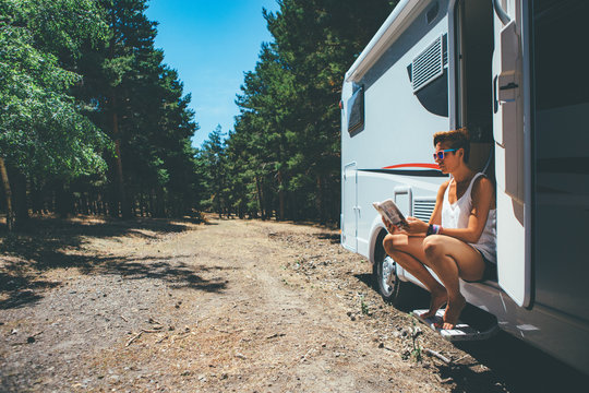 Girl reads on a motor home door step