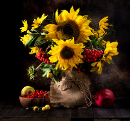 Still life bouquet of sunflowers in a vase, yellow autumn flowers, fruits and berries