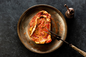 Raw steak ribeye on a metal plate and fork for meat