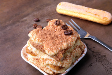 Piece of appetizing homemade tiramisu cake on plate in close up.