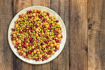 Beans, peas and hummus in a white plate on the table
