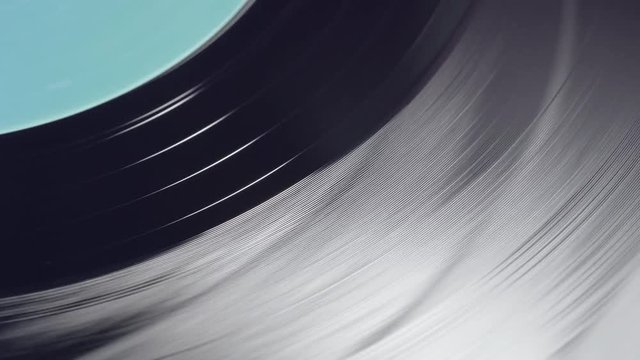 Fragment of a rotating black vinyl record player. Macro. View from above. The moment of a spinning vinyl plate. Turntable vinyl record player. Audio equipment for disc jockey.