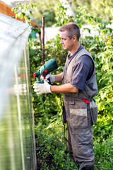 Positive man in overalls with spray gun in hand