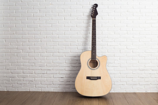 Acoustic guitar over brick wall white background with copy space © suriya