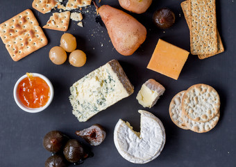 Cheese snack board with crackers, pickles, pears and figs