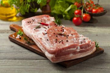 Raw bacon in whole on wooden background. © gkrphoto