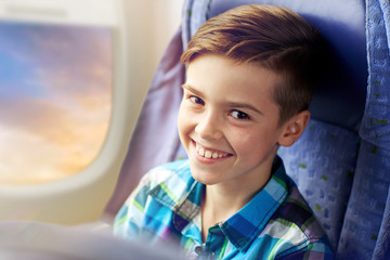 transport, tourism, road trip and people concept - happy boy travelling by plane over porthole background