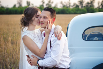 the bride is kissing the groom at sunset in the field against the background of the wedding car