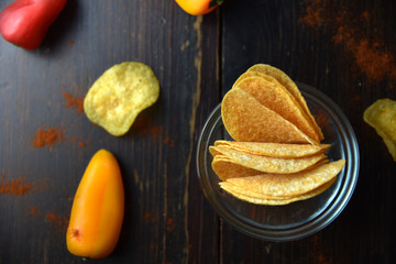Potato chips with paprika on dark wooden background