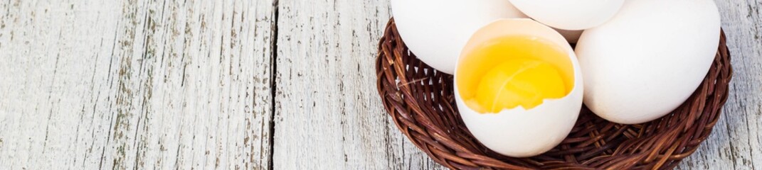 Banner of Broke One whole egg amongst white eggs in basket on a white background