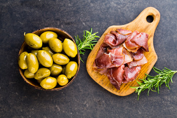 Prosciutto with rosemary on a black background.