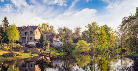 Fototapeta na wymiar Panoramic vernal landscape with a house near the lake