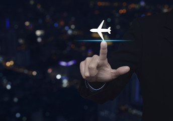 Businessman pressing airplane icon over blur colorful night light city tower, Business...