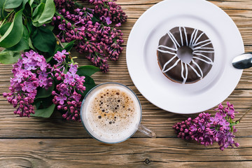 Obraz na płótnie Canvas coffee with milk, a wooden table, a lilac and a donut, a spring day