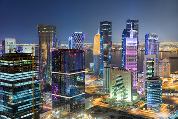 Das hell beleuchtete Zentrum von Doha, Katar, bei Nacht mit bunten Wolkenkratzern und der Westbay