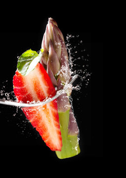 Green asparagus - asparagus tip, strawberry and mint on fork with splashes of water