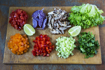 Set of chopped fresh vegetables with lime and beef on wooden board. Top view