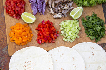 Tacos ingredients. Set of chopped fresh vegetables with beef, lime and tortillas on wooden board. Top view.