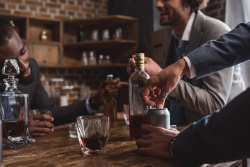cropped shot of multiethnic men in suits drinking alcoholic beverages together