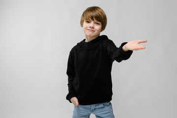 Portrait of adorable smilling little boy standing in studio offering his hand with hand in pocket...