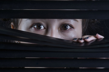 Oriental woman looking through a blind