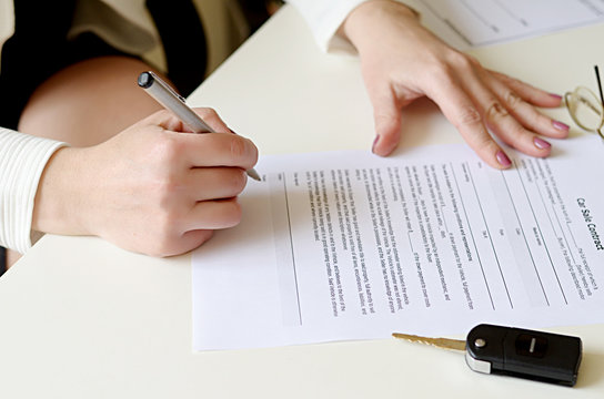 Woman signing car sale contract