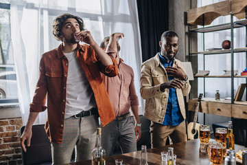 multiethnic male friends drinking tequila while partying together indoors