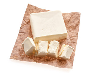 Top view of creamy piece of butter on a saucer over food paper background