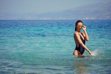 Fototapeta na wymiar beautiful young woman in bikini bathing and splashing happily in the sea at the resort