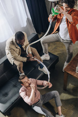 high angle view of smiling multiethnic friends drinking beer from beer bong