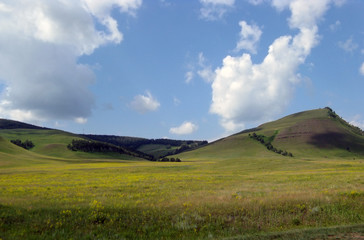Wide steppe with yellow grass under a blue sky with white clouds Sayan mountains Siberia Russia