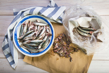 Limpiando pescado, sardinas frescas en la mesa de la cocina para la comida