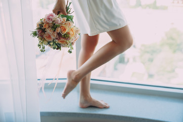 bride with a beautiful bouquet of different flowers in the hotel