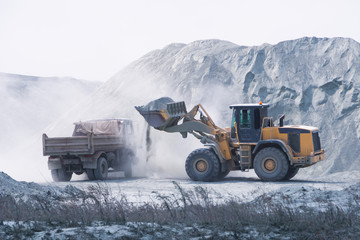 Excavator loading dumper truck with sand at a sand quarry