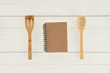 top view of textbook between two wooden spatulas on white table