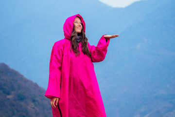 Fototapeta na wymiar beautiful and young girl in a pink raincoat against the backdrop of the mountains. the concept of active recreation and tourism in the mountains. trekking in Nepal Himalayas
