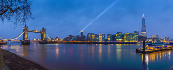 Obraz premium London, England - Panoramic view of London's most famous icons at blue hour. This view includes beautiful Tower Bridge, Shard skyscraper and office buildings with laser light