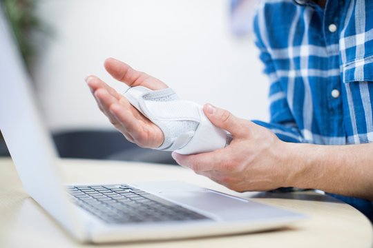 Close Up Of Businessman Using Laptop Suffering From Repetitive Strain Injury (RSI)