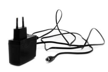 Black power adapter with cable and DC power supply connector for low current devices. on a white...