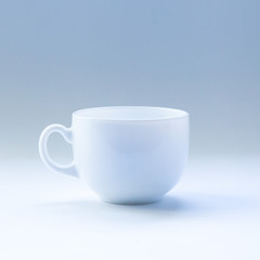 Empty light-blue cup with a handle on a light-blue background. Toning.